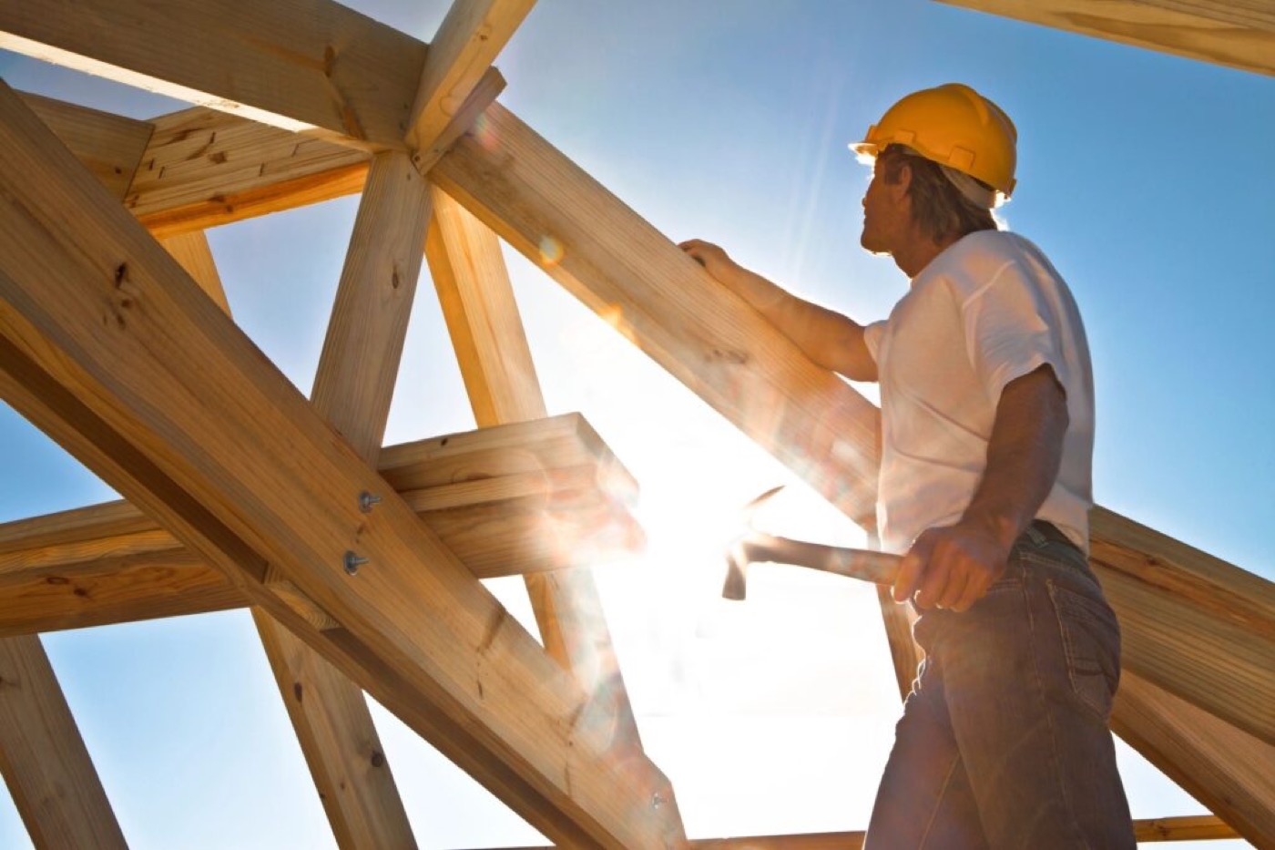 A Salisbury Construction carpenter framing a roof, sunlight behind